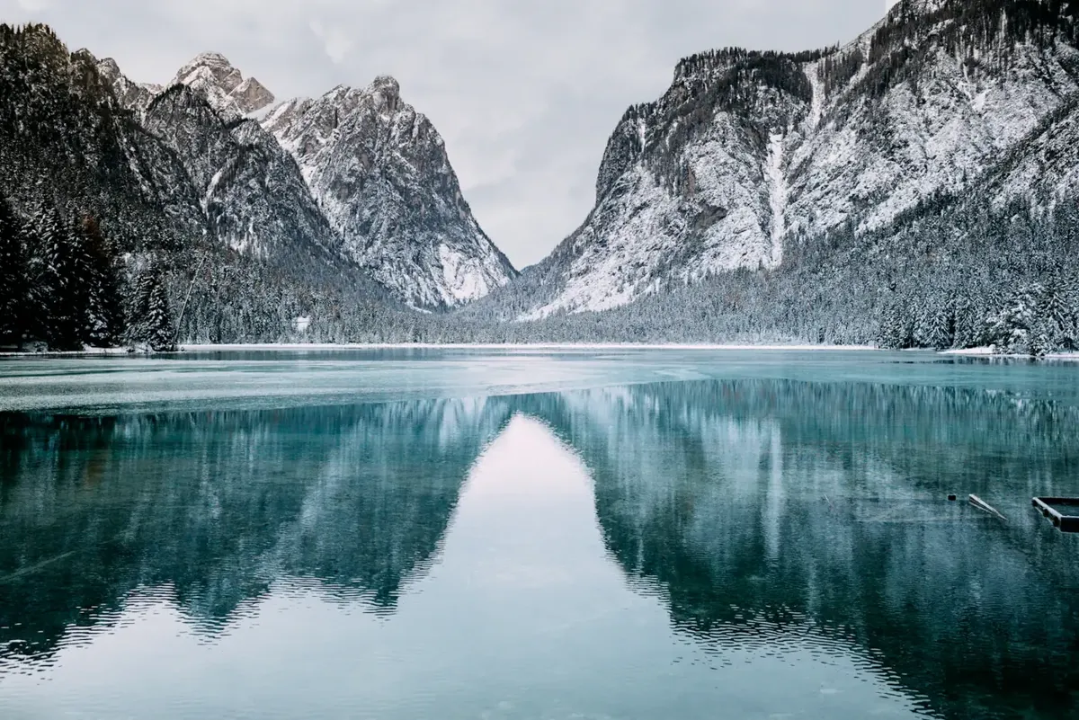 Lac turquoise entouré de montagnes enneigées sous un ciel bleu