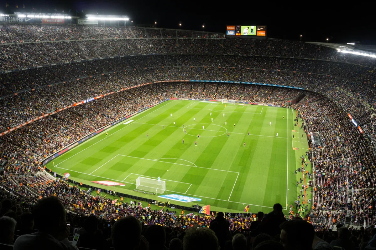 Vue des tribunes sur un terrain de football éclairé pendant un match en soirée